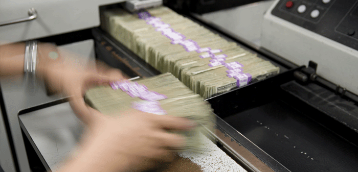 person processing bundles of cash in a sorting machine
