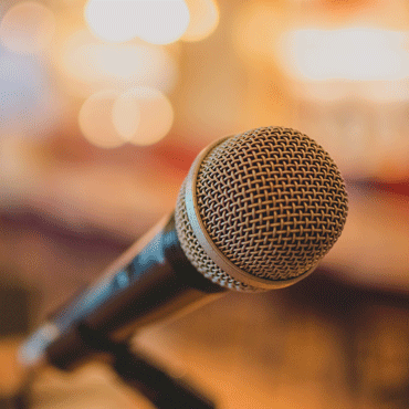 Photo of a microphone with audience blurred out